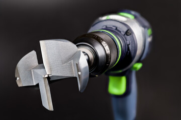 Close-up of steel Forstner bit in cordless drill on a black background. Metal professional cutting...