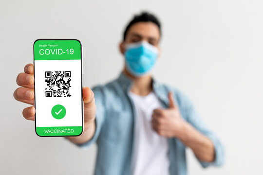 Vaccination certificate. Happy guy showing mobile app with qr code on cellphone screen, gesturing thumb up