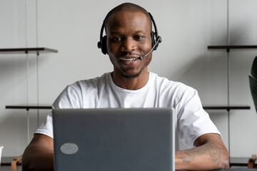 A black man is a customer service operator with a hands-free headset working in an office.