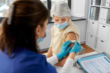 medicine, health and vaccination concept - doctor or nurse applying medical patch to vaccinated...