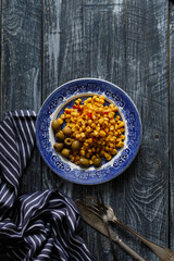 canned corn kernels with olives on a blue vintage plate. Wooden table.