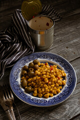 canned corn kernels with olives on a blue vintage plate. Wooden table.