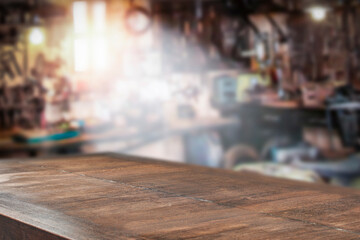A wooden table with a vacant space and the interior of a repair shop in the background  - 481367710
