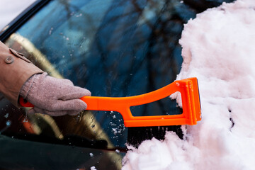Woman removing snow from car windshield