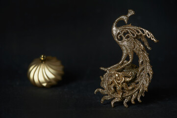 Golden Christmas tree toy in the form of a firebird with a ball on a dark background