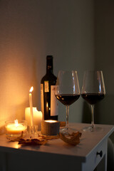 Candlelight date - two glasses of red wine and bottle of wine with candles on the table