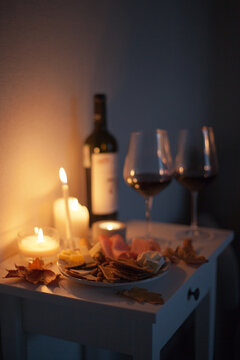 Candlelight date - two glasses of red wine and bottle of wine and appetizers with candles on the table