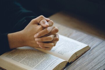 Naklejka premium Christian life crisis prayer to god. Women Pray for god blessing to wishing have a better life. Hands praying to god with the bible. believe in goodness. Holding hands in prayer on a wooden table.