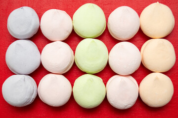 Pattern of multi-colored pastel marshmallows on a red background, top view, flat lay. Colorful marshmallows as a background.