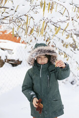 Portrait of a boy dressed in warm clothes, in winter in snowy weather on the street