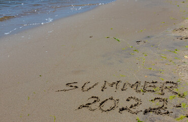 The inscription on the sand Summer symbolizes a summer 2022 vacation at the sea