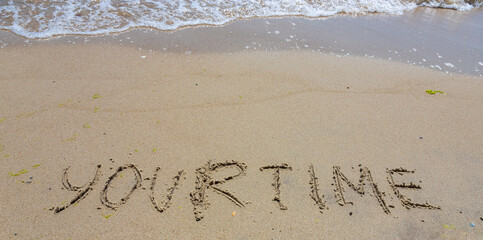 Handwriting word your time written in the sand
