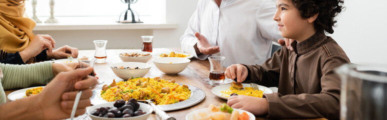 arabian boy smiling during dinner with muslim family at home, banner.
