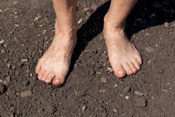 Barefoot woman stands on the raw soil with copy sace for your text