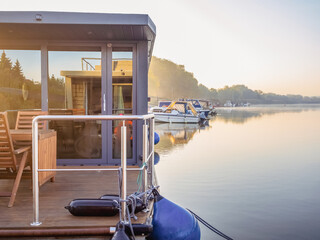 houseboat on a river in a early sunny morning. floating house is a pleasant place for rent for...