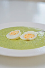 Vegetarian diet and vegan food, green healthy broccoli soup on a plate on a clean kitchen table. Tasty and nutritious meal, lunch or dinner