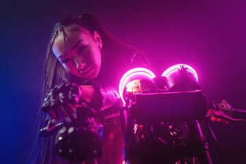 Plakat Girl a motorbiker near the old motorcycle in the neon lights.