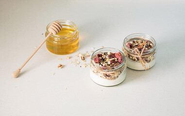 Homemade granola parfait. Quick healthy breakfast greek yogurt, honey, granola with dried berries and nuts in glass jar on stone table. Copy space, selective focus.