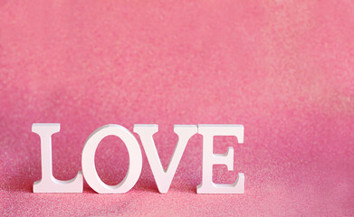 The word LOVE is made of white letters on a pink glitter background. Valentine's Day, love, soft boke