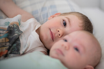 Niños bebés hermanos jugando en la cama de sus padres abrazados