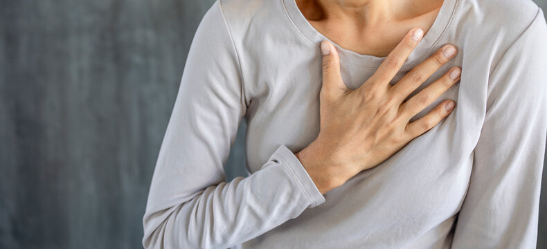 Woman suffers from chest pain and touches her heart area, heart attack