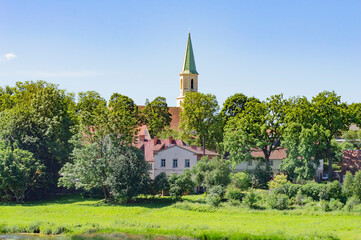 St Catherine church tower, old houses with tiled roofs, green trees and grass on the river bank, typical old european summer cityscape