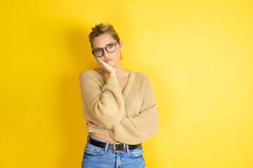 Young beautiful woman wearing casual sweater over isolated yellow background thinking looking tired and bored with crossed arms