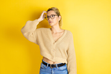 Young beautiful woman wearing casual sweater over isolated yellow background confuse and wonder...