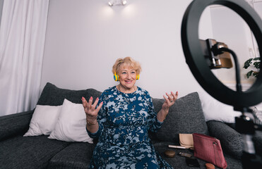 an elderly woman in the living room on the couch shoots a video for the network.actively...