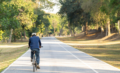 A man in a riding helmet rides a bicycle on the street. The scent of nature, trees along the way evening sun shining