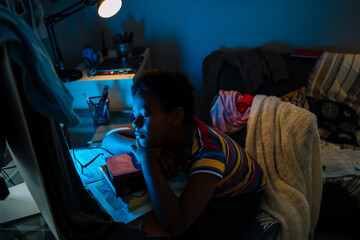 Black boy looking at computer screen while doing homework
