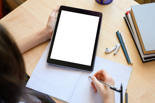 A tablet with a blank white display in the hands of a schoolgirl. Top view, copy space.