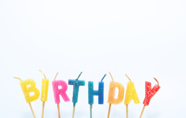 A candle with the word " BIRTHDAY" in bright colors against a white background.