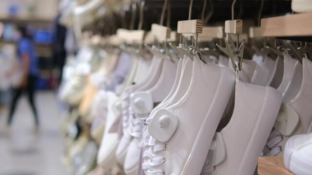 Many white shoes hanging in a row in a trendy stylish mass-market store, cheap footwear shopping on sale