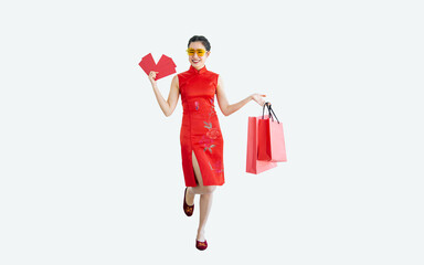 Beautiful cheerful Asian woman wearing red costume, smiling, holding angpao, shopping bag on white background with copy space, present sale promotion advertisement, celebrate Chinese New Year.