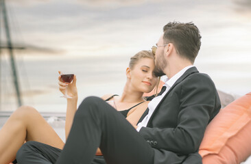 Romantic vacation and luxury travel on Summer Day. Lovely couple in love on a yacht drinking wine on luxury yacht in the sea at sunset. People celebrating wedding anniversary on boat trip.