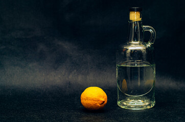 A beautiful bottle of vodka and a lemon next to it on a black background.