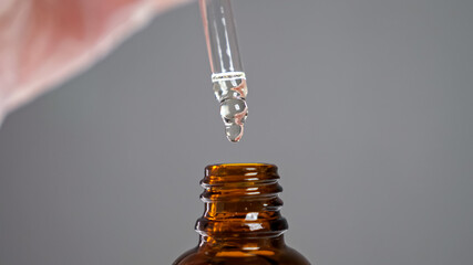 Laboratory specialist opens bottle with new developed aloe extract holding dispenser pipette with...