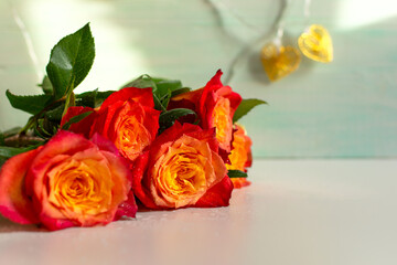 Red orange roses on a white mint wooden background. A fresh bright bouquet with dew drops. Happy Valentine's Day, Happy Mother's Day. The concept of a birthday, anniversary, wedding. Copy space