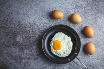 Fried eggs in a pan and fresh eggs on the table