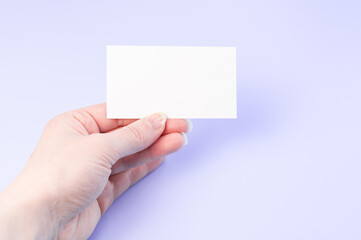 Female hand with a blank card isolated on purple background. One hands with empty white card.