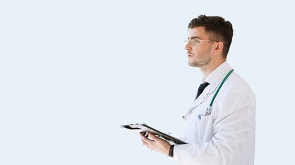 Healthcare, medical: Portrait of young medical doctor isolated over grey color background