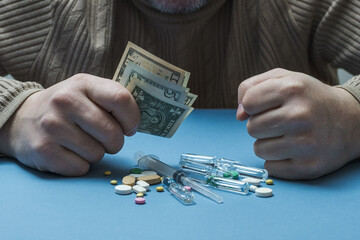 A man is sitting at a table, holding money in his hand, medical preparations are in front of him.