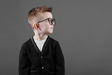 Portrait of a smart and serious child boy in glasses on a grey background close-up. Concept of school education, science and innovation, business development. copy space