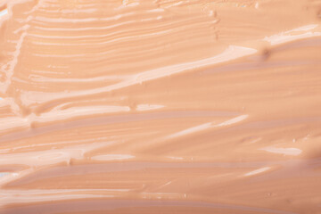Smear of liquid foundation,beige color.Cosmetics abstract background.Selective focus.