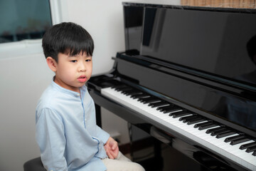 Asia boys wearing shirt look at camera and make unhappy face. Boring time on practicing music at school. Musician kid feeling sad during class. Cannot pass testing. Education and learning concept