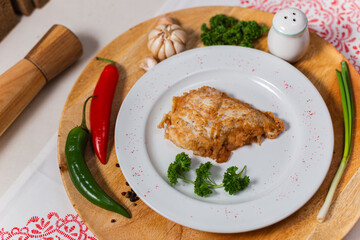 meat in dough on a white plate and a wooden background
