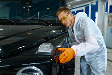 Fototapeta na wymiar Serious repairman inspecting painting quality of vehicle