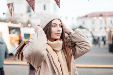 Beautiful happy young stylish woman in fashionable winter outerwear in a vintage knitted hat with a...