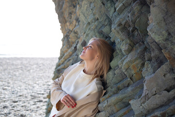 portrait of a young beautiful woman on the seashore against the background of rocks